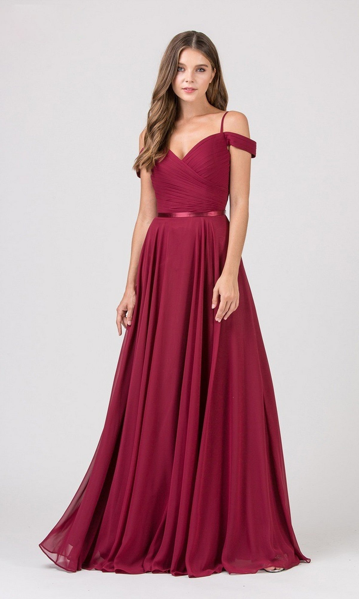A woman wears the Eureka 7611 long burgundy prom dress, featuring an off-the-shoulder chiffon design with a ruched fitted bodice and flowing skirt, standing against a plain light background.